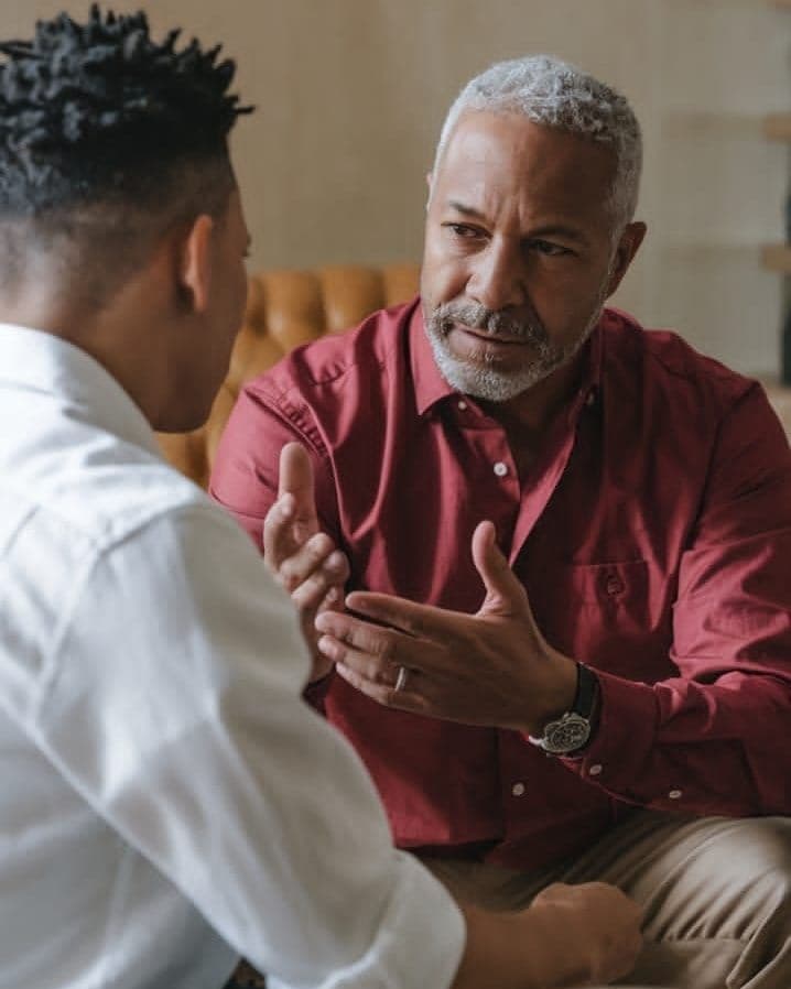 An older mentor in conversation with a younger man, illustrating generational legacy